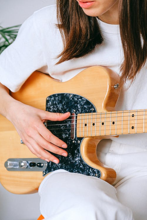 Free Woman in White Crew Neck T shirt Playing Brown and Black Electric Guitar Stock Photo